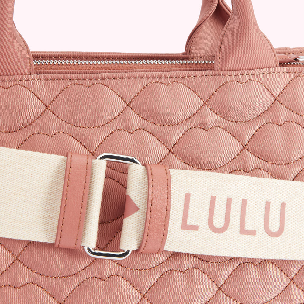 Close-up of a dusty rose Lulu Guinness quilted handbag with a cream and rose-coloured strap.

