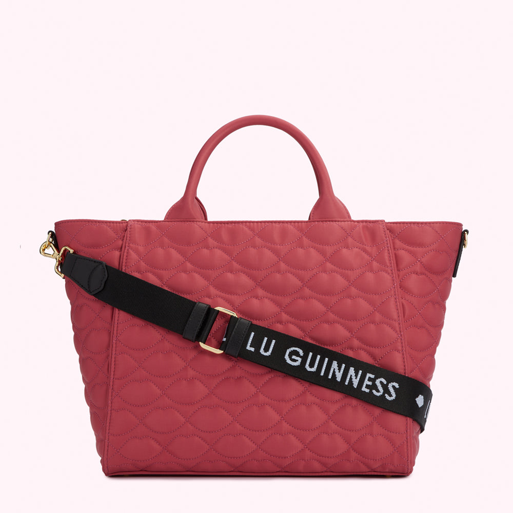 Pink quilted tote bag with black and white logo strap.
