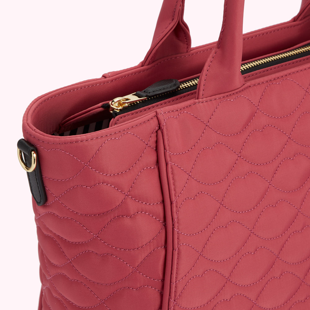 Close-up of a quilted pink tote bag with gold zipper.