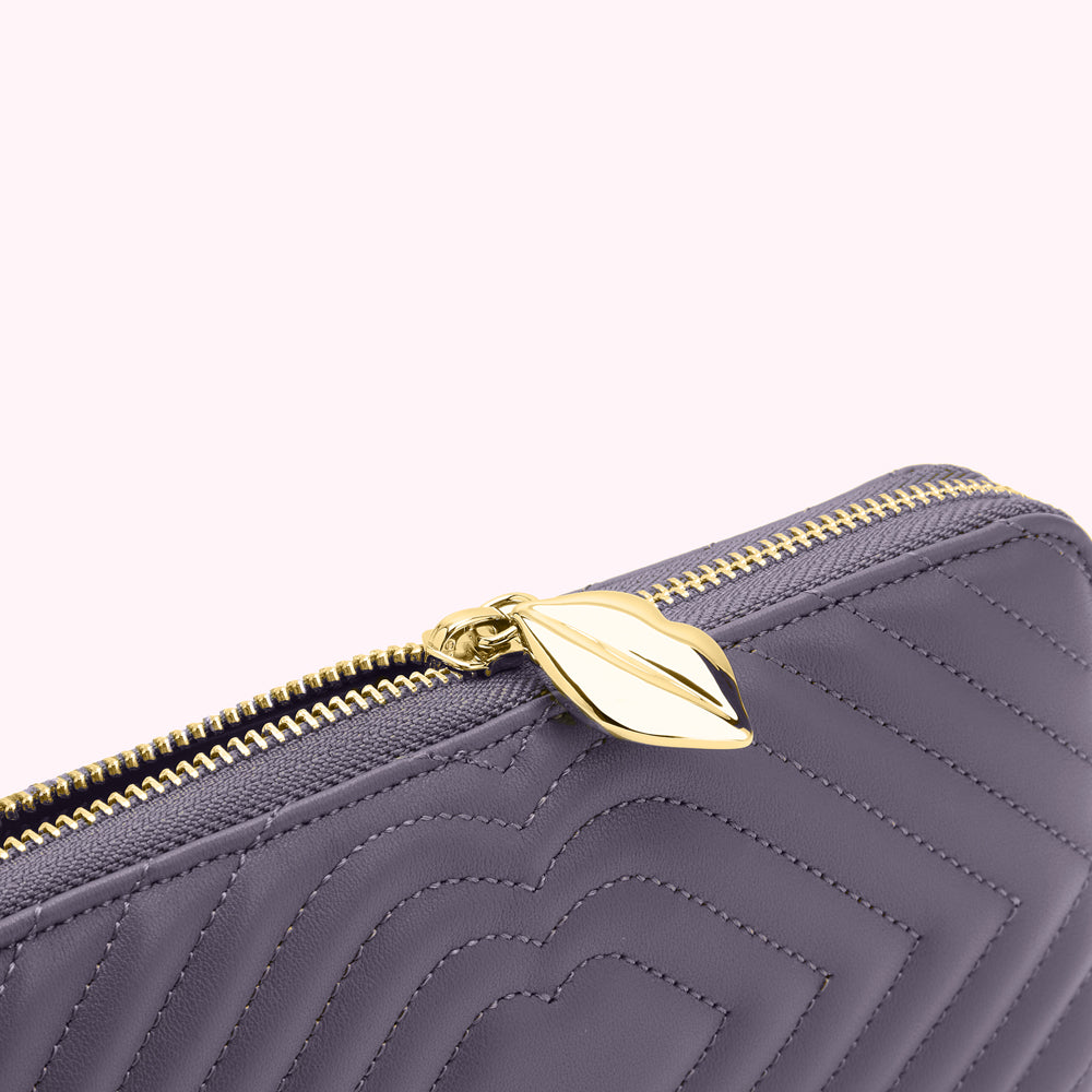 Close-up of a purple quilted leather zipper wallet with a gold zipper pull.