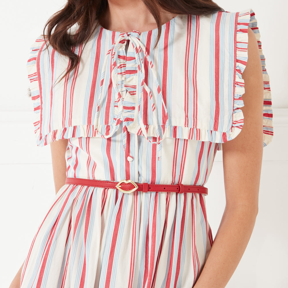 Close up image of a women wearing a red, white and ivory striped dress and a red leather belt with a gold lip buckle on her waist.