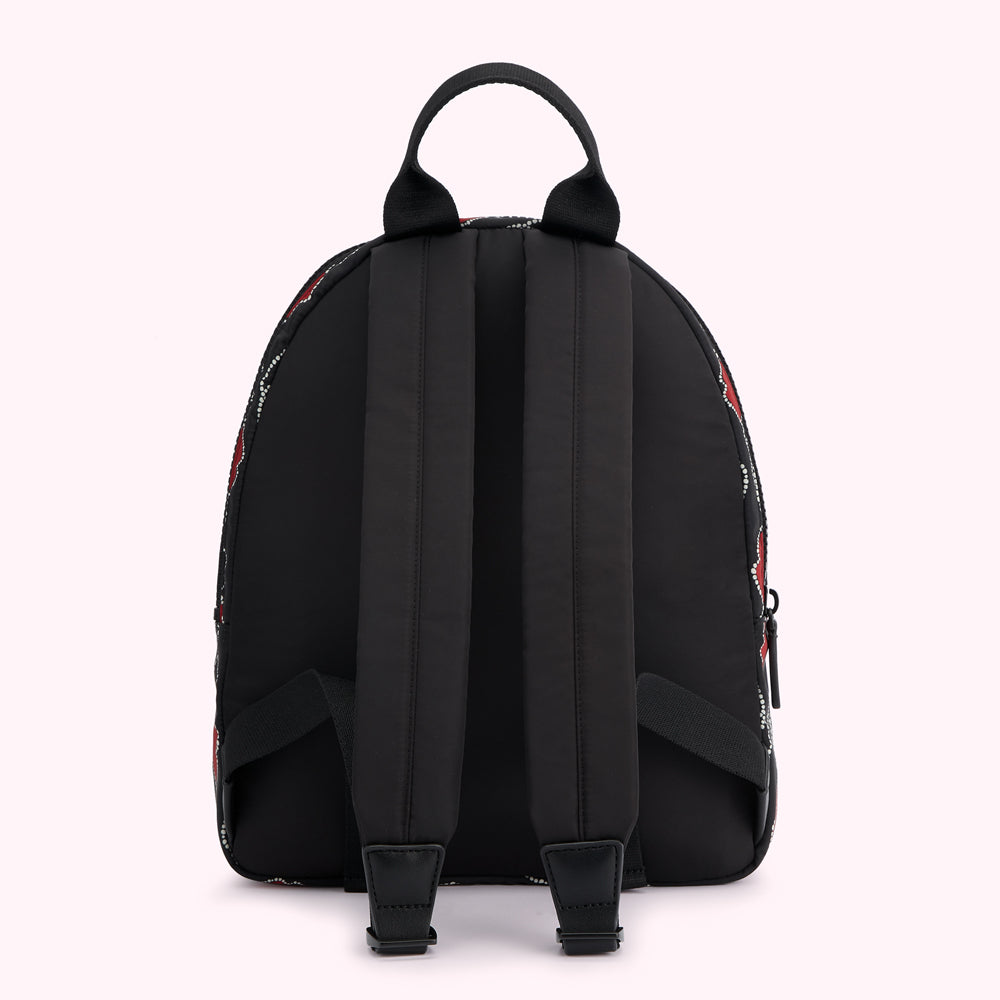 Black backpack with red and white patterned sides, viewed from the back.

