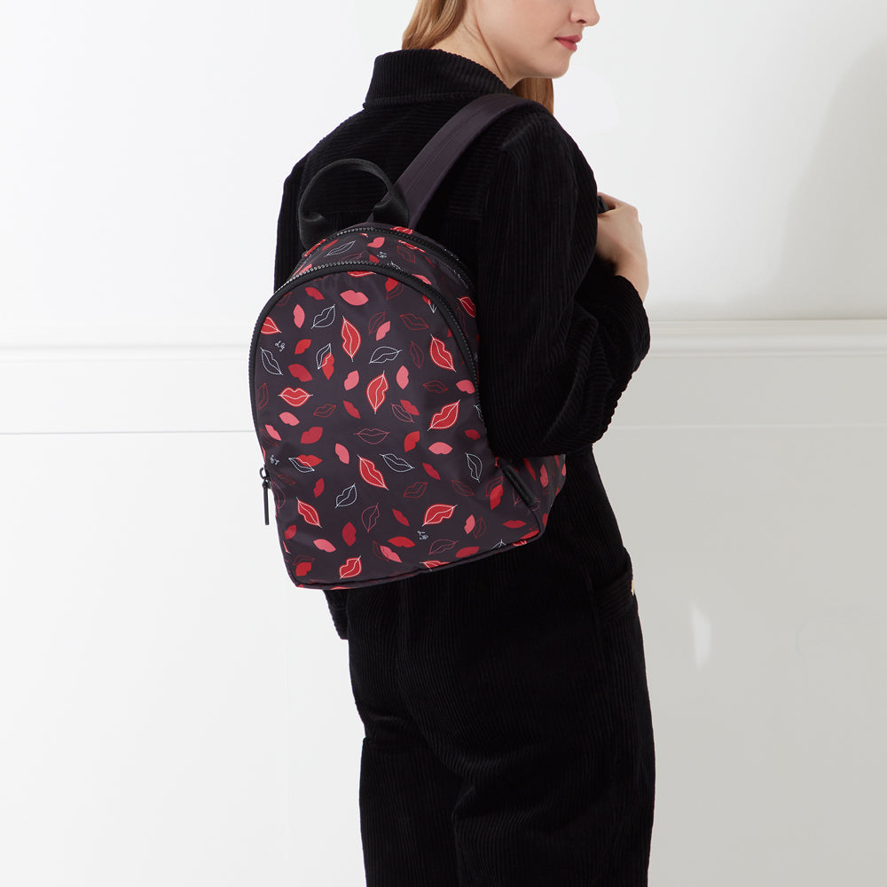A black backpack with a red lips pattern on a white background.