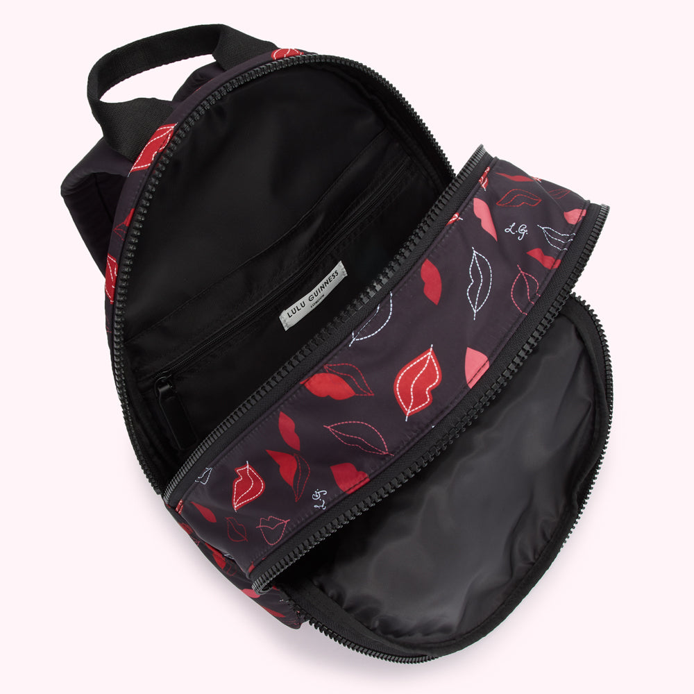 Open Lulu Guinness black backpack with red lips print.
