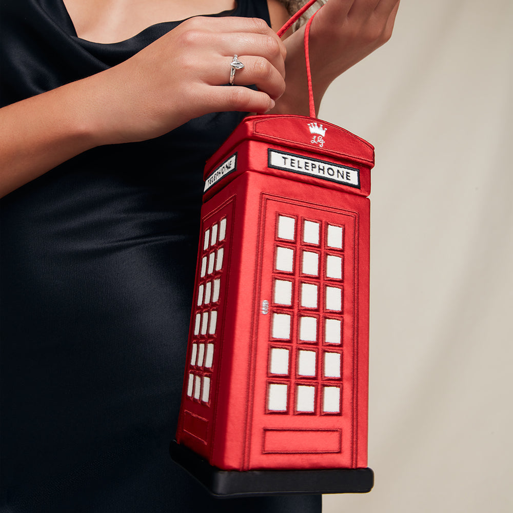 Red telephone box-shaped handbag held by a person