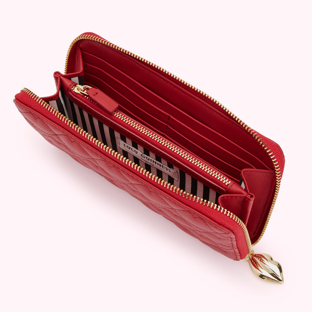 Red quilted Lulu Guinness zip-around wallet open to show interior compartments and gold zipper.

