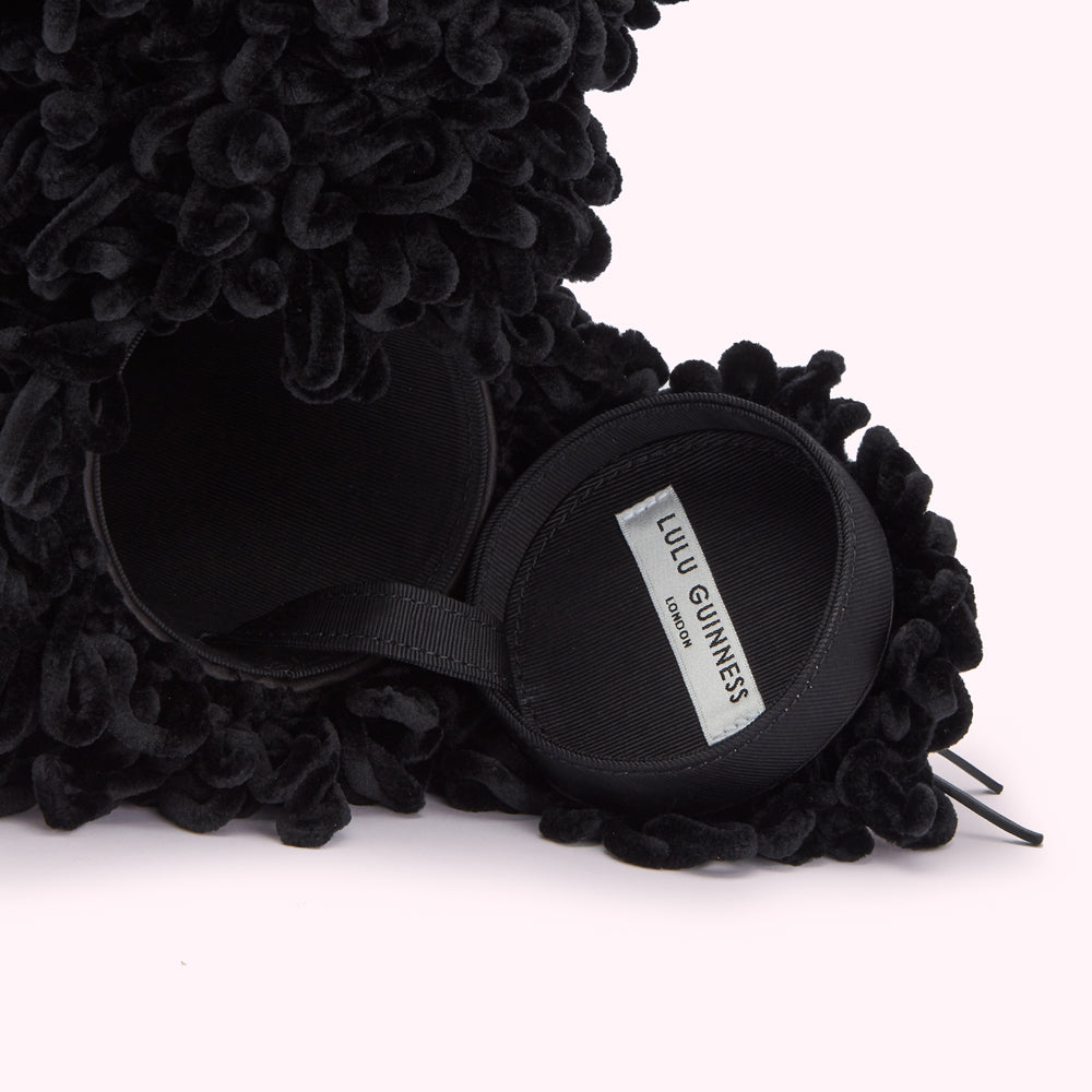 Black velvet dog-shaped bag with a textured exterior and a black satin interior. The bag is open, revealing the brand label, black against white "Lulu Guinness London".
