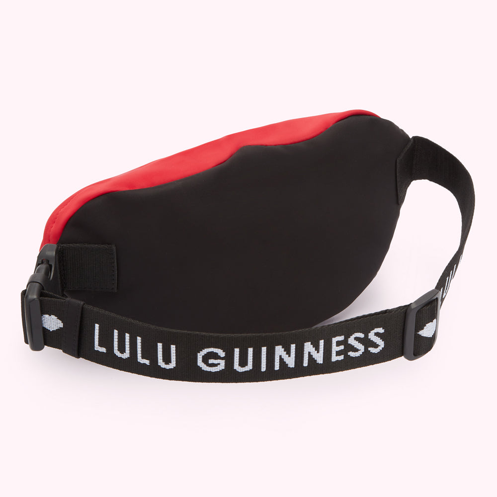 Red and black Lulu Guinness bum bag, viewed from the back.
