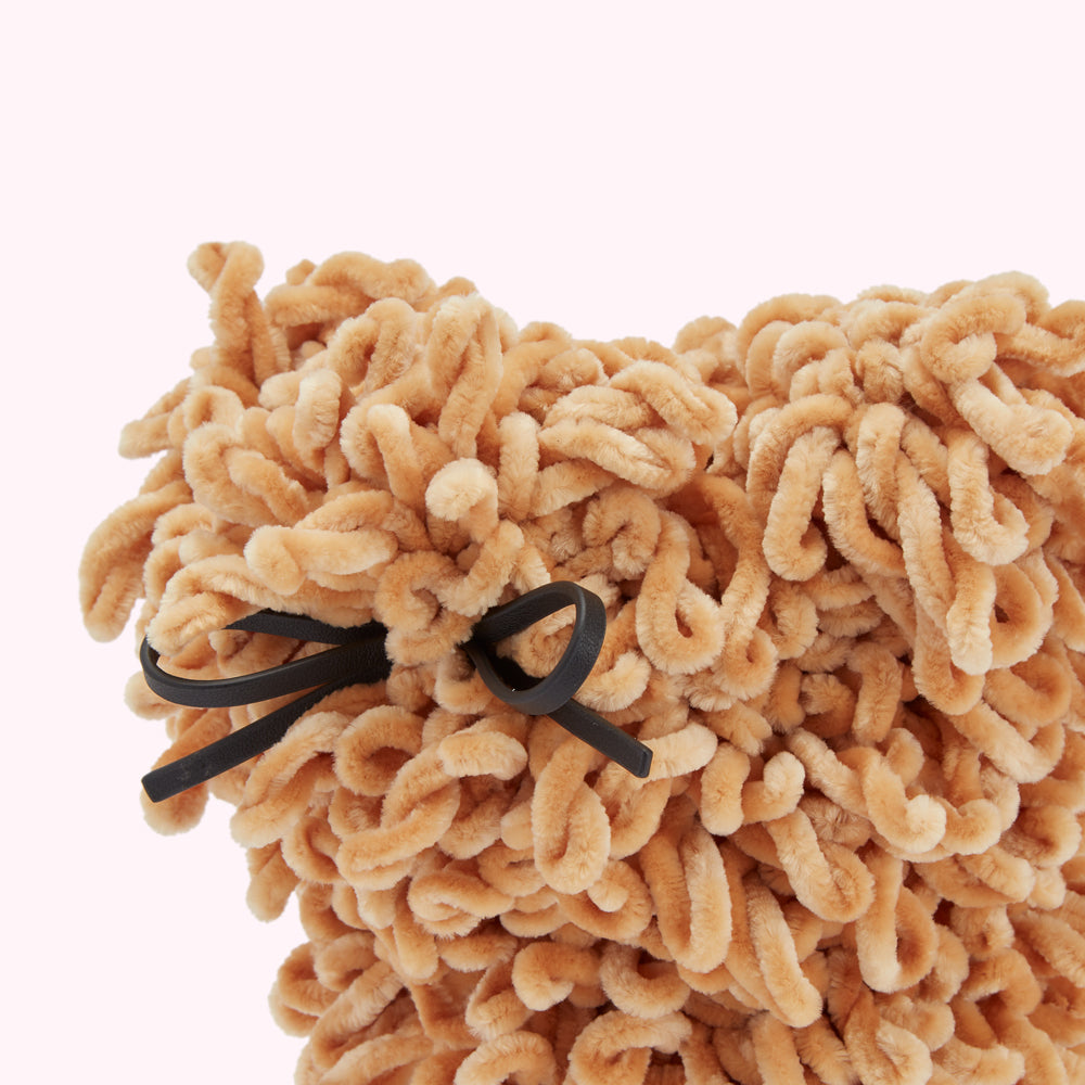 Close-up of a tan, fluffy textile item with a black ribbon.
