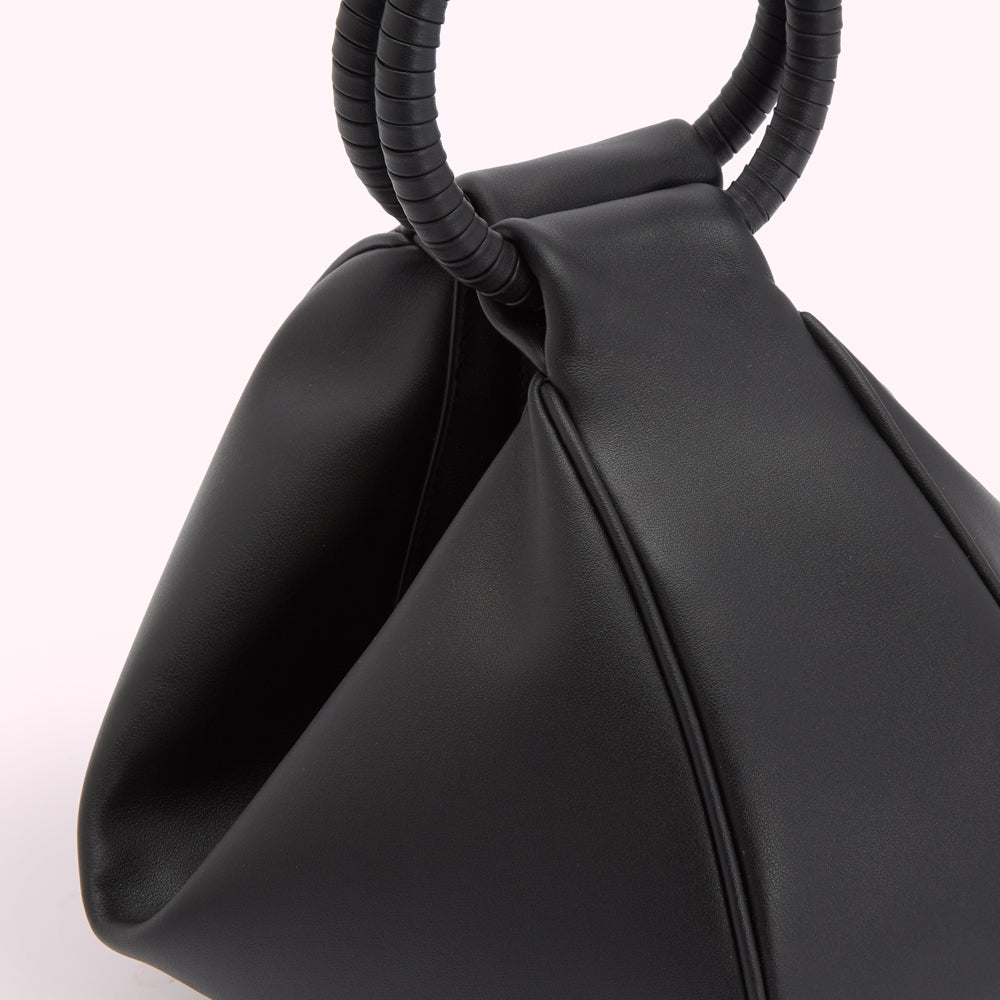 Close-up of a black, triangular-shaped handbag with double ring handles.
