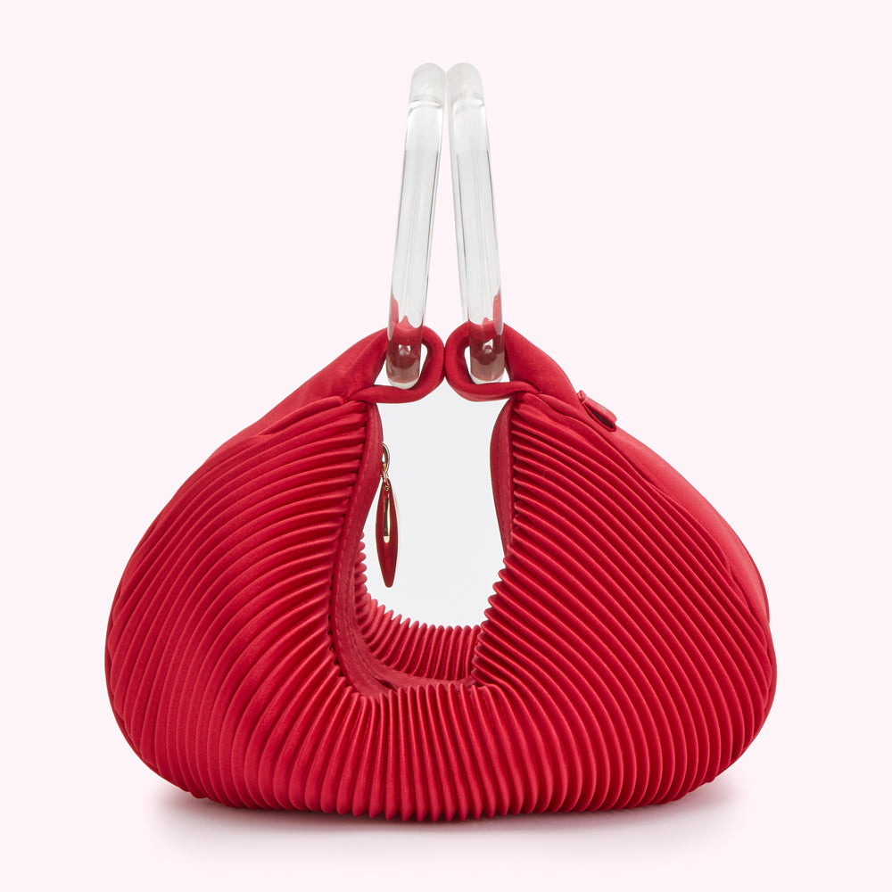 Red pleated handbag with clear acrylic handles.
