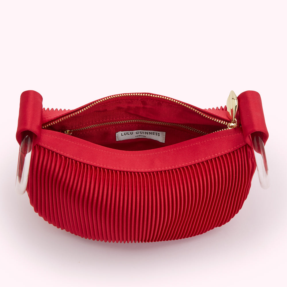 Open red pleated Lulu Guinness handbag with clear handles.
