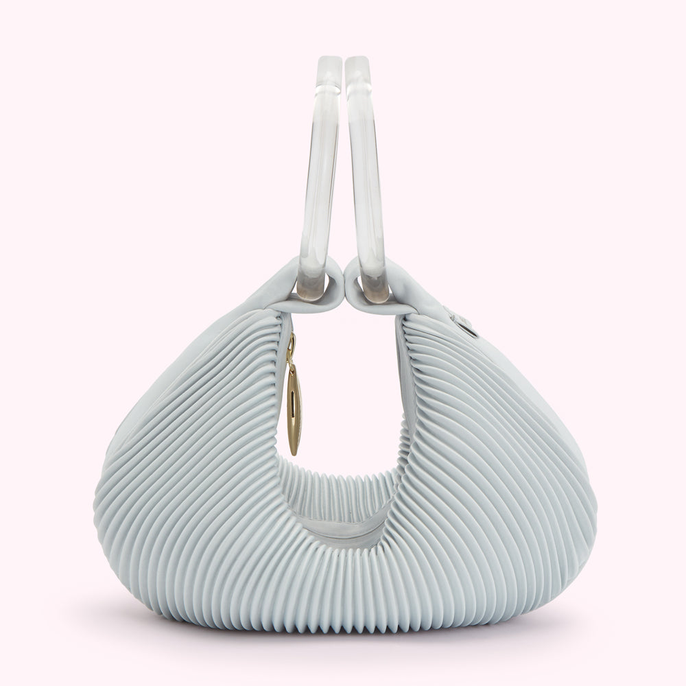 Light blue pleated handbag with clear handles and gold detail.

