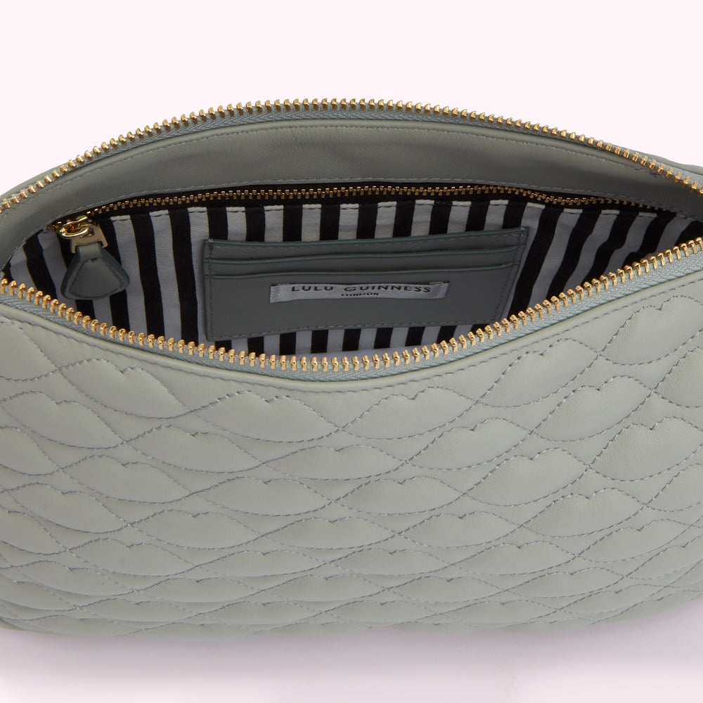 Sage green quilted Lulu Guinness pouch open to reveal black and white striped lining and brand label.
