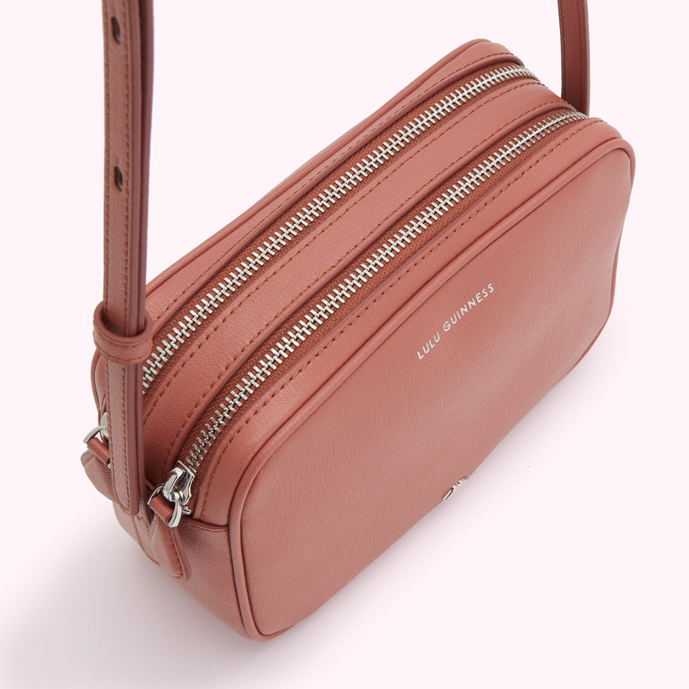 Dusty rose Lulu Guinness crossbody bag with two zippers.