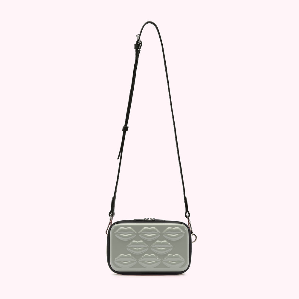 Sage green crossbody bag with black strap and lip-shaped embellishments.
