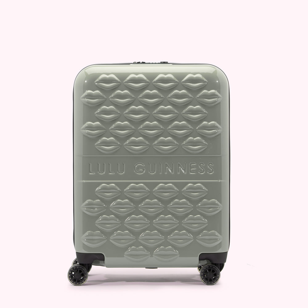 Sage green Lulu Guinness suitcase covered in a pattern of embossed lips.