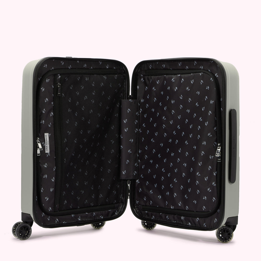A light grey carry-on suitcase open to reveal its black interior with zippered compartments and a repeating pattern.