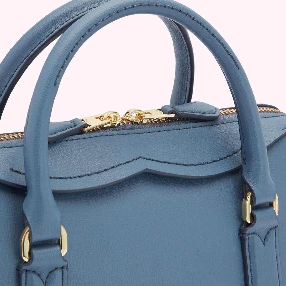 Close-up of a blue leather handbag with gold hardware.
