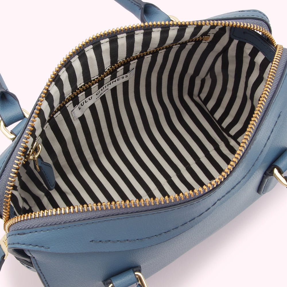 Interior of a blue Lulu Guinness handbag with a black and white striped lining.