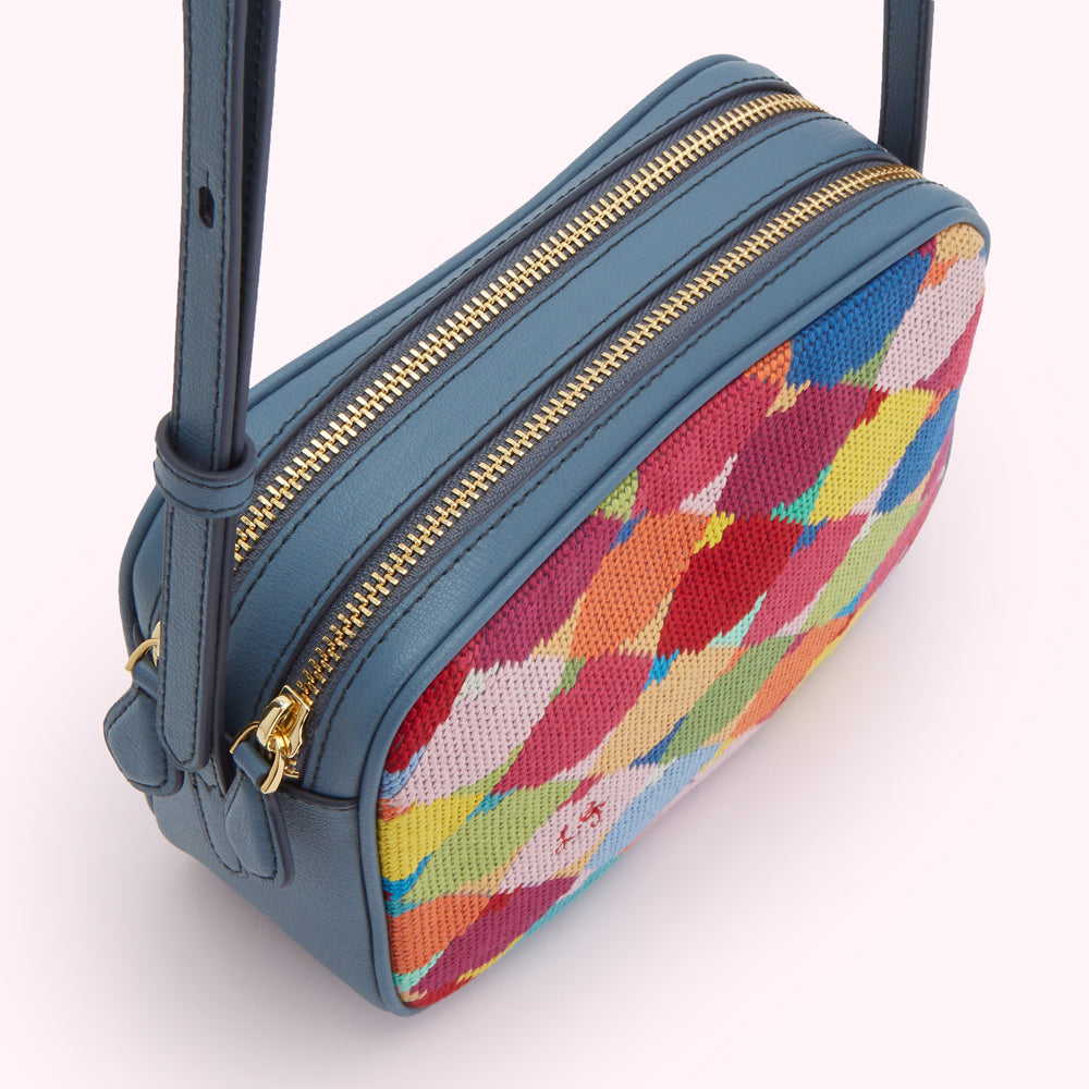 A blue crossbody bag with a multi-coloured, patterned flap.