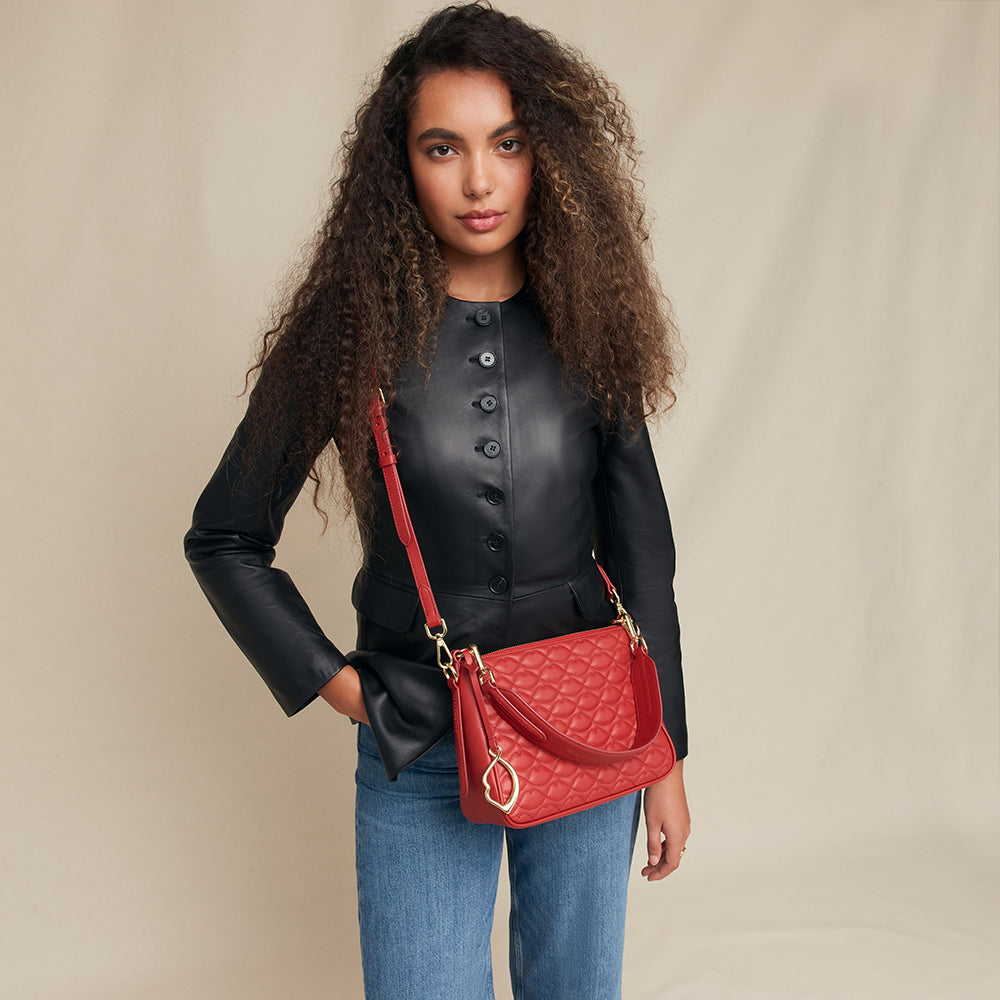 Woman holding a red handbag against a beige background