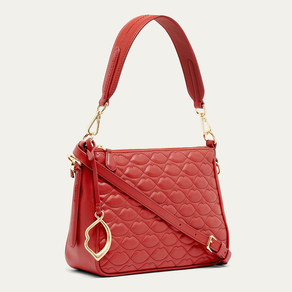Red quilted handbag with gold accents on a light gray background