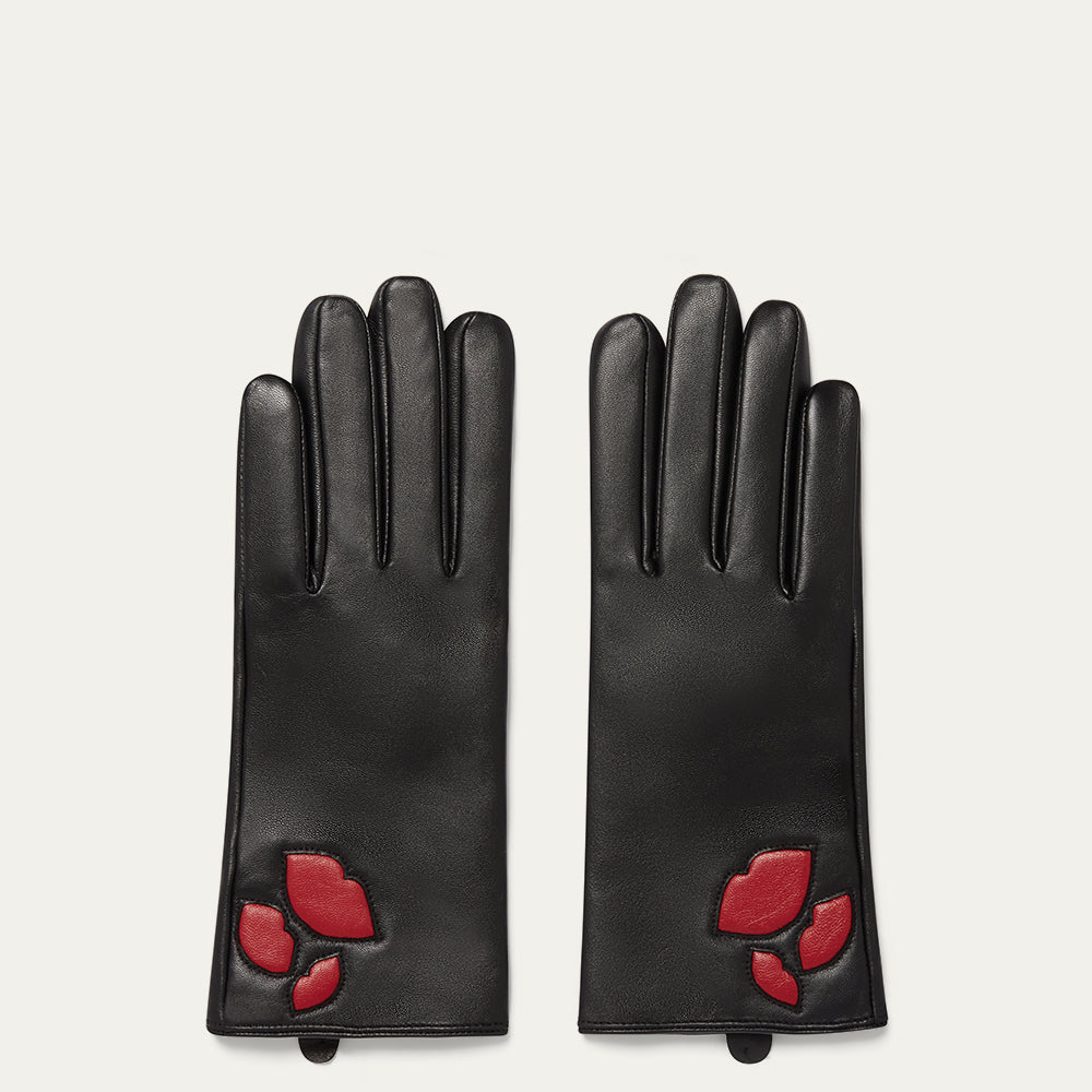Pair of black leather gloves with red lip designs on a light gray background