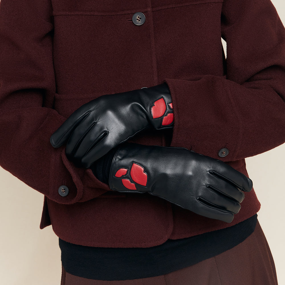 Black gloves with red accents worn by a person in a maroon coat.