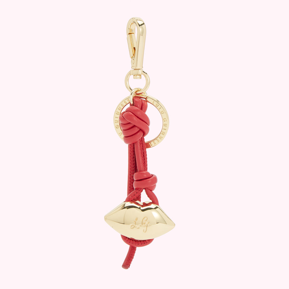 Red leather keychain with gold lip charm and logo.
