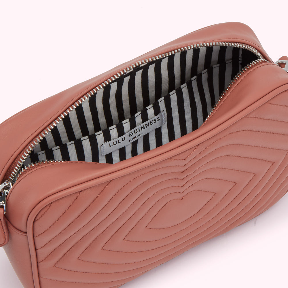 Dusty rose quilted crossbody bag with black and white striped interior and Lulu Guinness London label.
