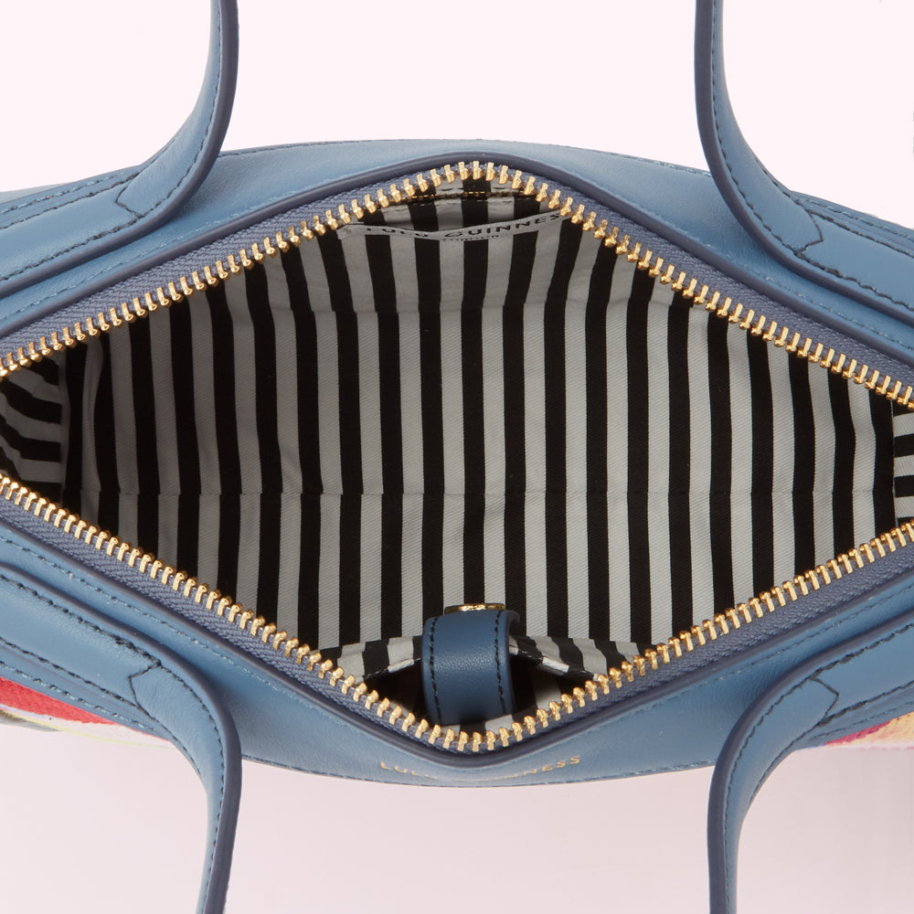 Inside of a blue Lucy Guinness handbag with a black and white striped lining.