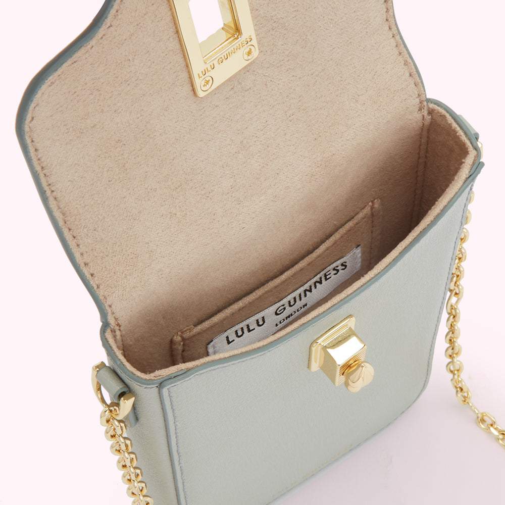 Interior view of a pale teal Lulu Guinness crossbody bag with gold clasp and chain.