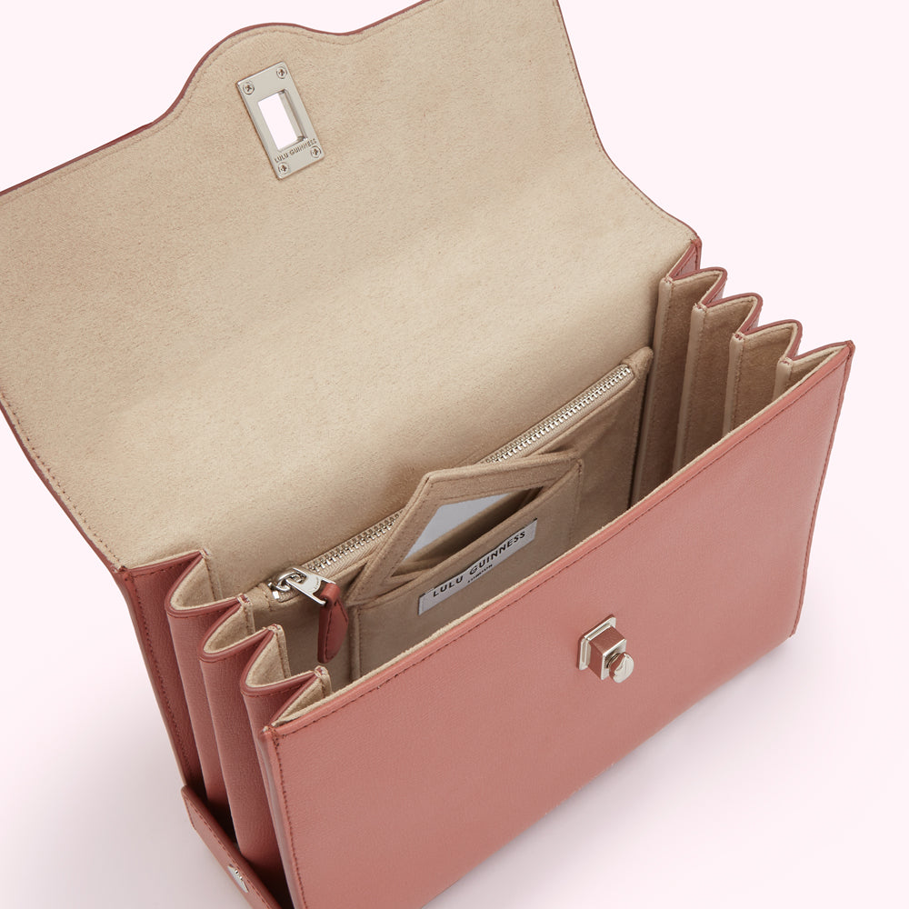 Open dusty rose Lulu Guinness satchel bag showing beige interior with multiple compartments and zippered pocket.
