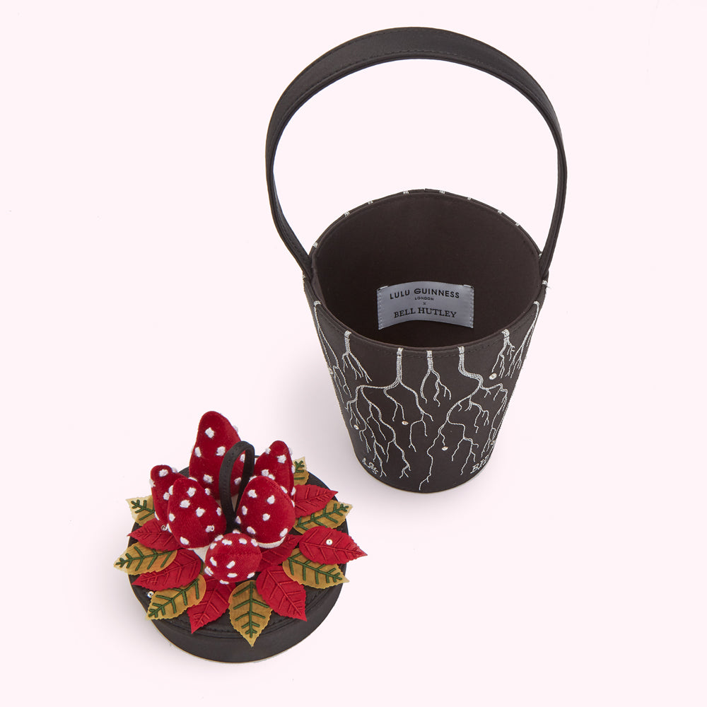 Black bucket bag with embroidered roots and accompanying red mushroom felt decoration.