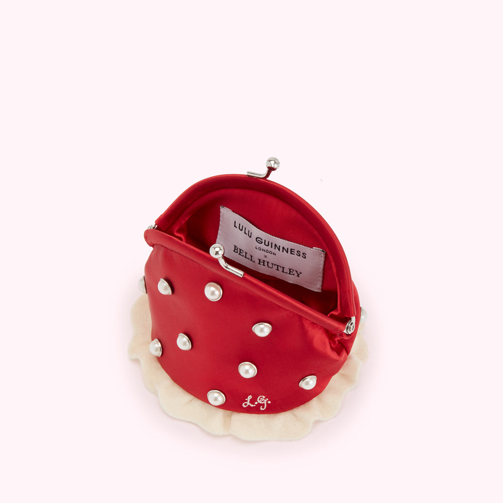 Red Lulu Guinness x Bell Hutley purse with pearl detailing and off-white ruffled trim, open to show interior.