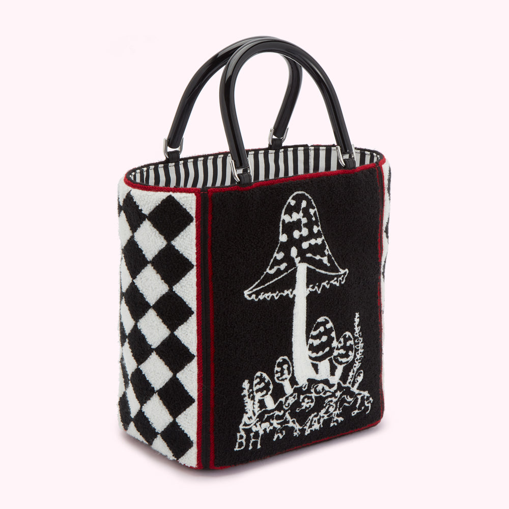Black and white harlequin and mushroom-print tote bag with black handles.