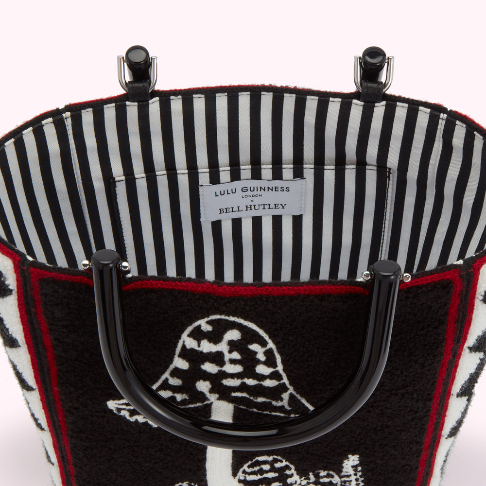 Inside of a Lulu Guinness x Bell Hutley tote bag featuring a black and white striped lining and a black fuzzy exterior with a mushroom design.