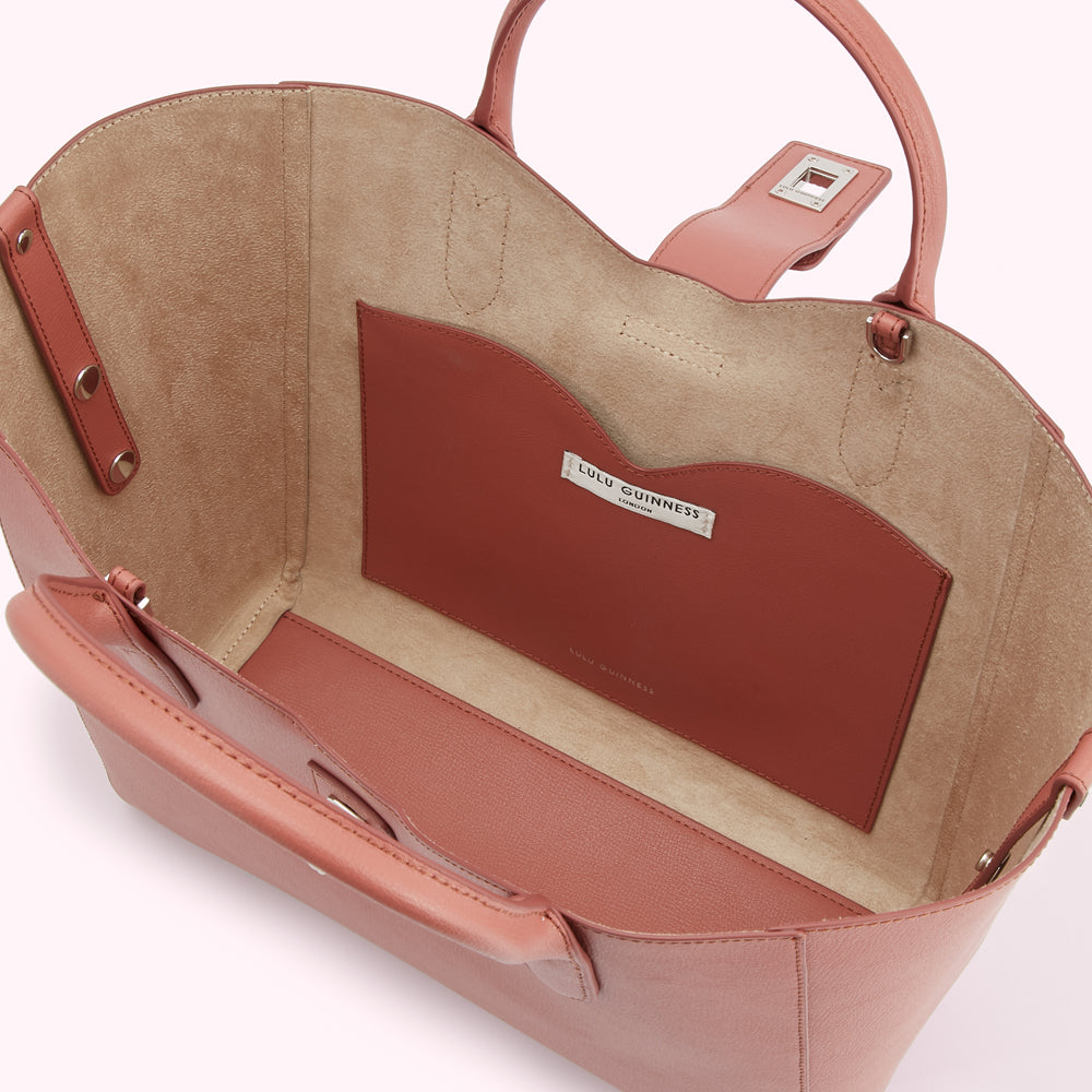 Inside view of a dusty rose Lulu Guinness tote bag showing the beige suede interior and a smaller dusty rose pocket with the brand's logo.