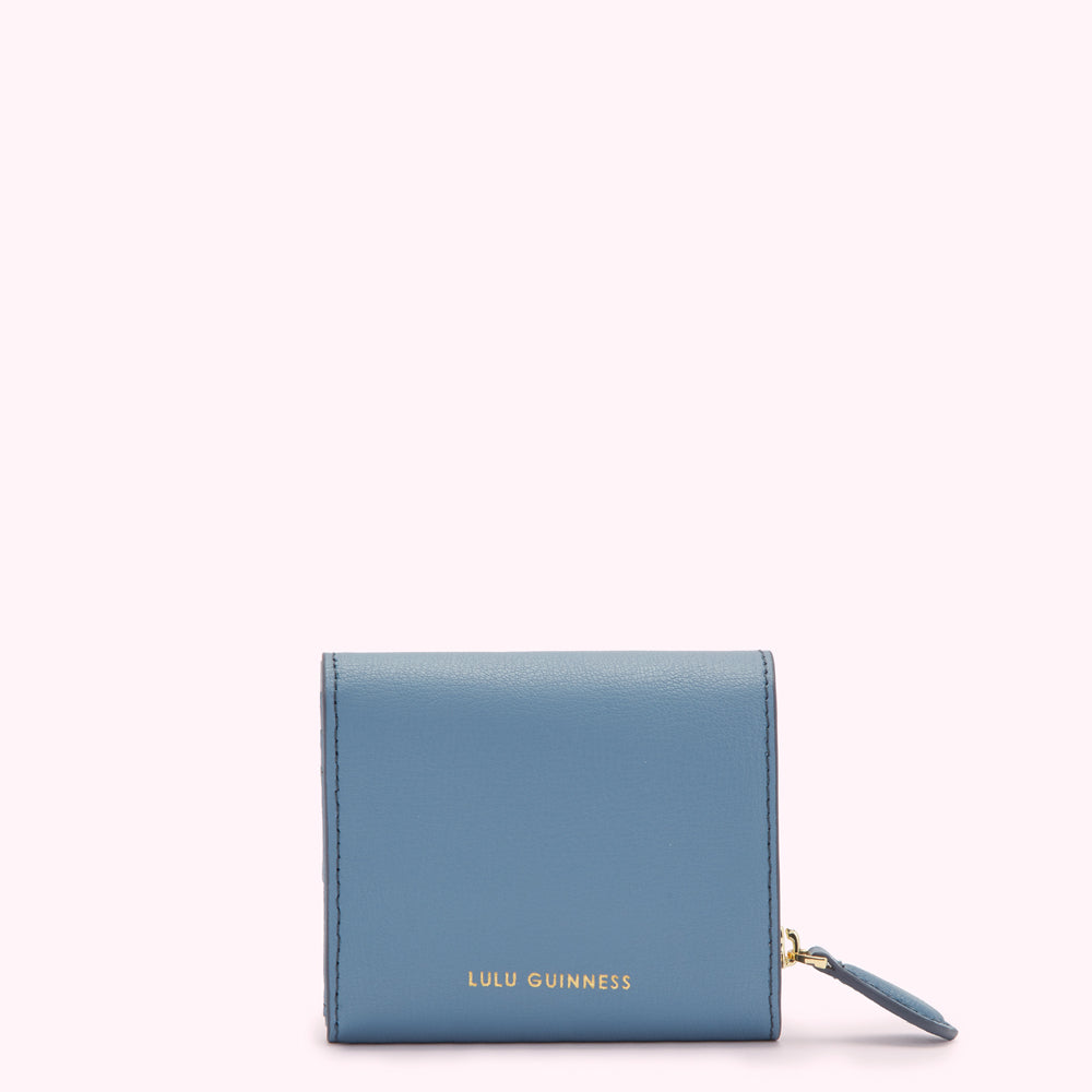 A small, powder blue, Lulu Guinness zip-around wallet on a white background.
