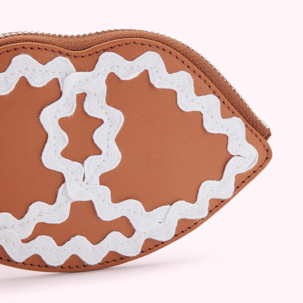 Close-up of a brown leather lip-shaped coin purse with white decorative stitching.
