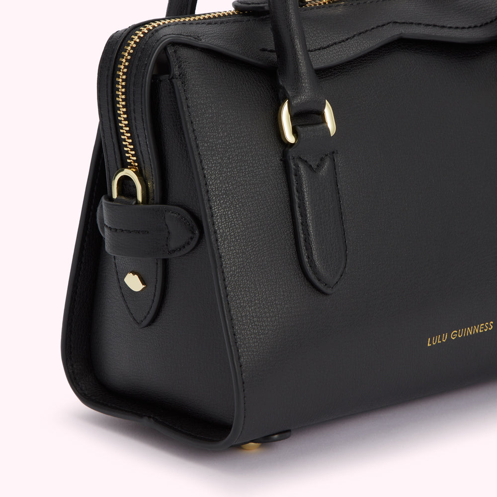 Close-up of a black Lulu Guinness satchel bag with gold hardware.
