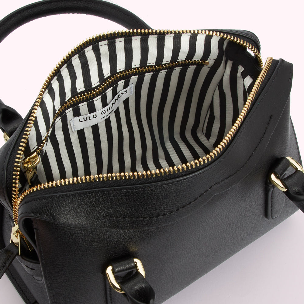 Black Lulu Guinness satchel bag open to reveal black and white striped interior.

