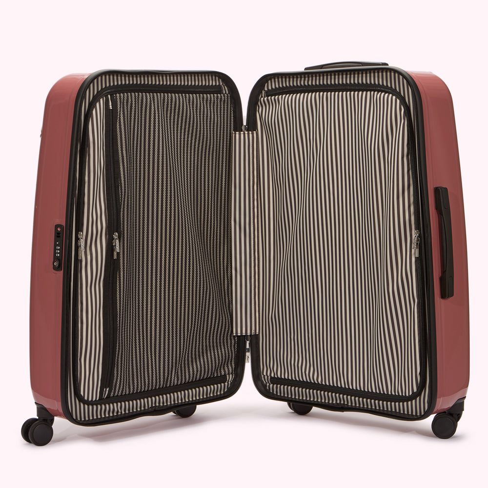 Open rose-coloured suitcase with black and white striped interior lining.
