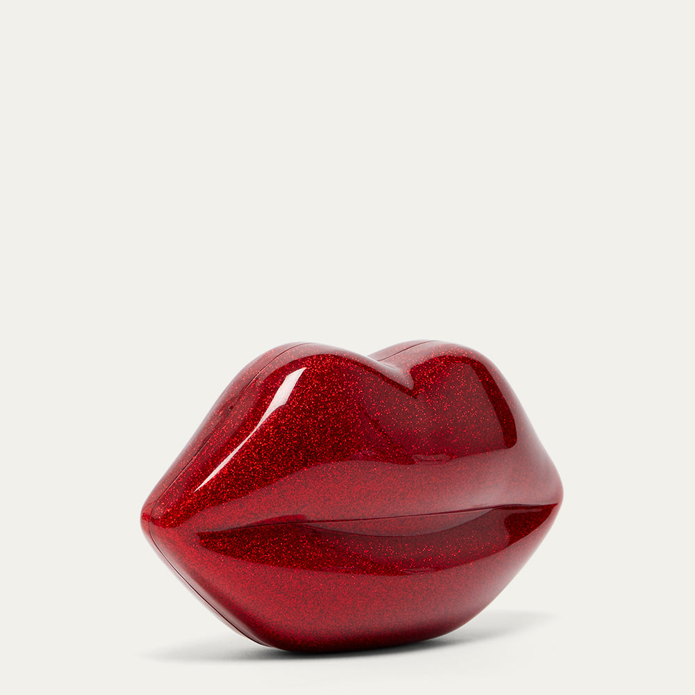 Red glittery lips-shaped clutch bag on a light grey background