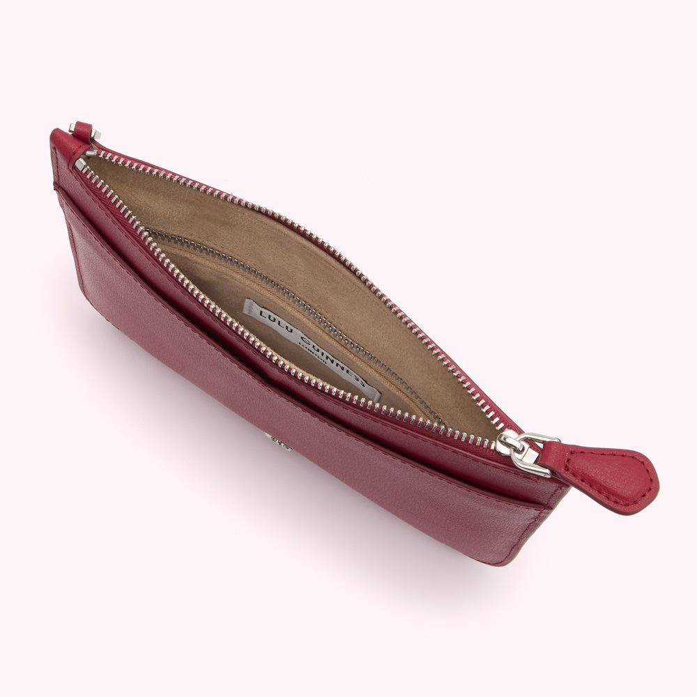 Open red leather zip pouch with beige lining and Lulu Guinness label.
