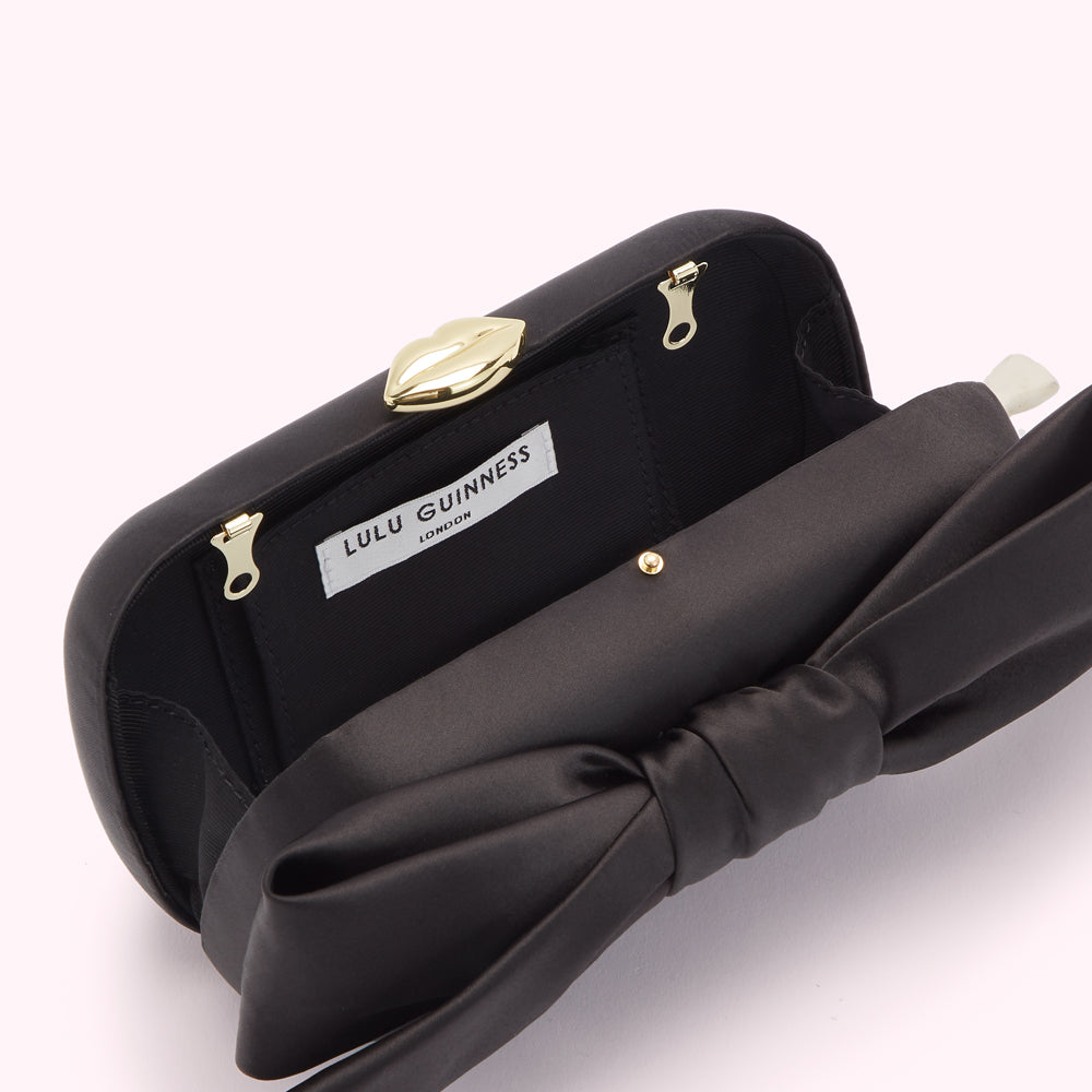 Black Lulu Guinness satin clutch with a large bow and gold lip clasp.
