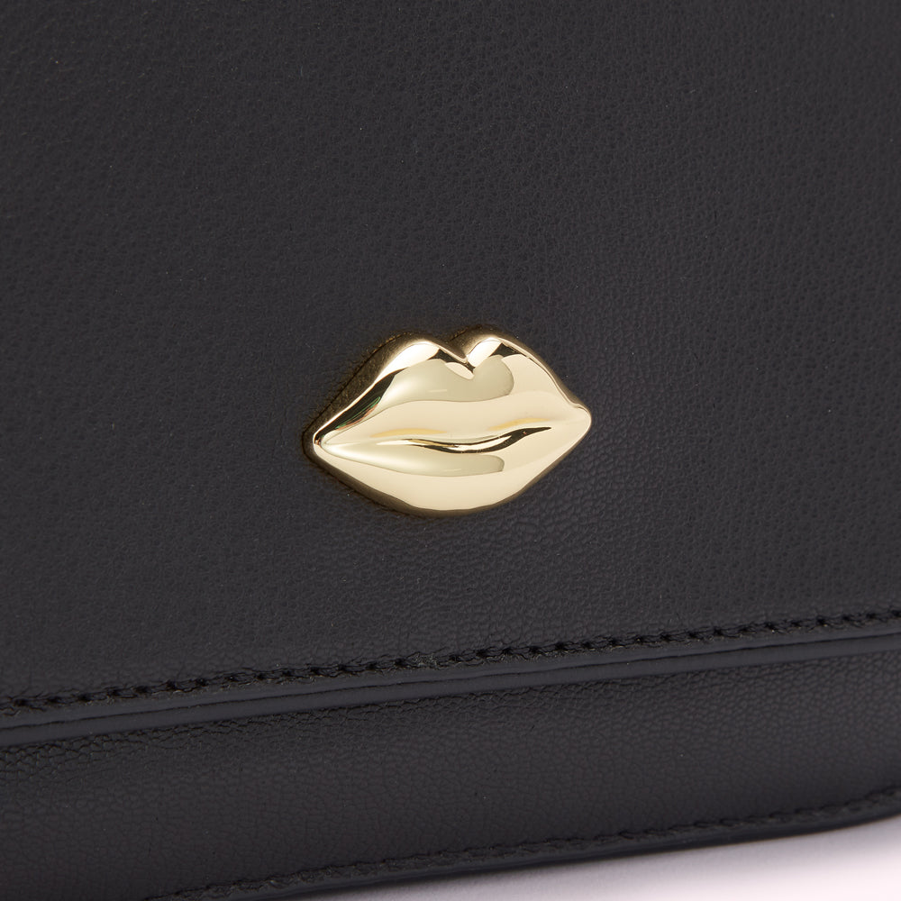 Close-up of a black leather purse or wallet with a gold lip-shaped detail.
