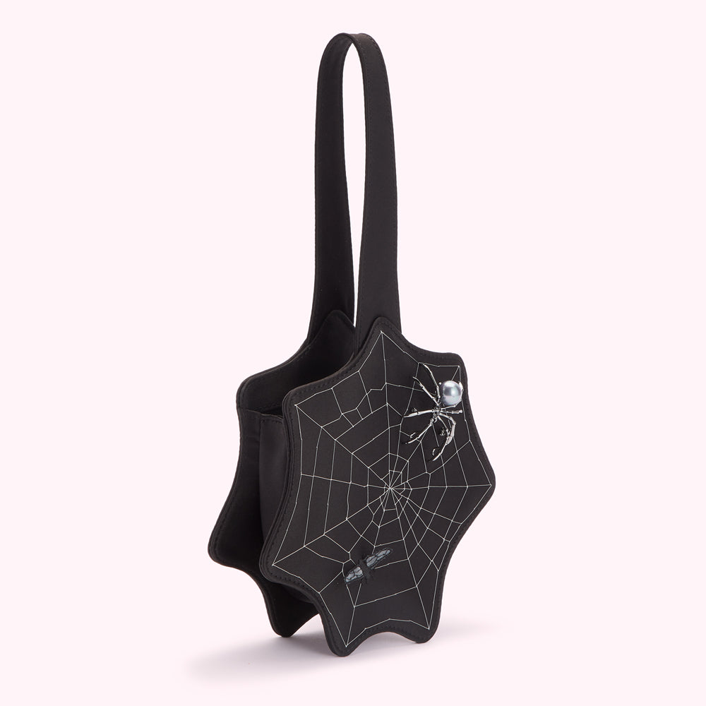 Black web-shaped handbag with spiderweb design and jewelled spider and fly accents.
