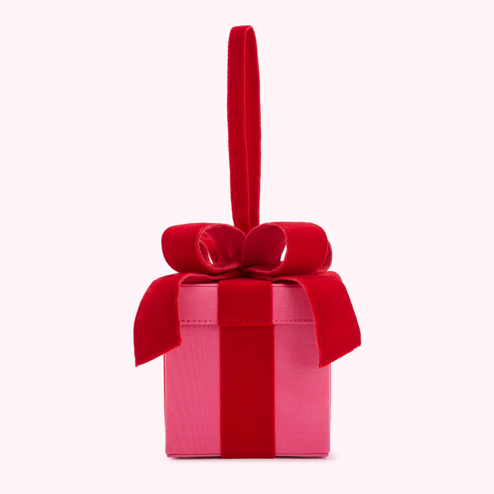 Pink present box with red velvet ribbon and bow, and a red velvet handle.

